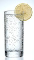 Sparkling water or soda in tall glass with fresh lemon slice garnish, isolated on white background. Perfect for beverage, refreshment, and drink-related design projects.