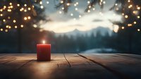 Red candle glowing on rustic wooden table against winter mountain landscape backdrop with magical bokeh lights creating cozy atmospheric scene at dusk.