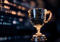 Golden trophy cup glowing against dark background with bokeh lights, dramatic close-up shot highlighting metallic details and reflective surface.