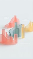 Colorful translucent geometric shapes and cylinders in coral pink, mint green and yellow arranged on white background for modern design projects.