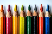 Vibrant colored pencils arranged in rainbow order against white background, macro close-up view showing wood texture and sharpened tips for art and creativity concepts.