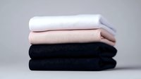 Neatly folded stack of cotton t-shirts in white, pink and black colors on neutral background, minimalist fashion and clothing concept for retail and online stores.