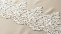 Delicate white lace trim with ornate floral and rose motifs on neutral background. Elegant embroidered edging for wedding, fashion, textile, and craft design projects.