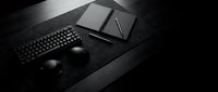 Modern black workspace setup with laptop, wireless mouse and keyboard on dark desk surface for professional office design and productivity concepts.