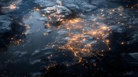 Aerial night view of glowing city lights through clouds, creating luminous network pattern across dark landscape. Satellite perspective of urban development.