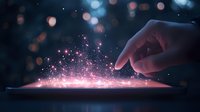 Magical glowing pink sparkles emerge from touchscreen device as finger interacts with digital display, creating ethereal light effect against dark background.