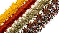 Colorful spice powder lines with star anise and peppercorns arranged in rows on white background for culinary cooking and seasoning applications.