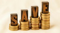 Wooden letter blocks spelling SAVE on ascending stacks of golden coins representing financial growth and money saving strategies for investment planning.