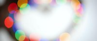 Colorful bokeh lights creating dreamy blurred circles on soft white background for festive celebrations and holiday decorations.