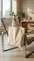 Blank canvas tote bag hanging on modern office chair in bright workspace with natural light for eco-friendly shopping and sustainable lifestyle branding.