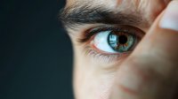 Close up macro shot of bright blue human eye with detailed iris pattern and long eyelashes against dark background, showing natural beauty and vision concept.