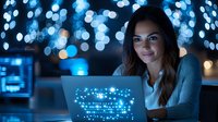Young woman working late at night on laptop with glowing blue bokeh lights in background, smiling while analyzing data on screen in modern office.