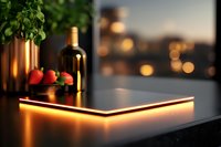 Modern kitchen counter with glowing LED strip light creating ambient orange illumination, fresh strawberries and wine bottle against blurred city lights background.