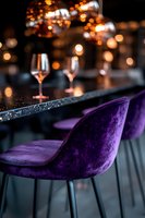 Luxurious purple velvet bar chairs at elegant restaurant counter with wine glasses and ambient bokeh lighting creating romantic atmosphere for fine dining experience.