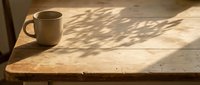 Ceramic mug on wooden table with natural sunlight and shadow, morning coffee scene for lifestyle and beverage content.