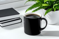 Black coffee mug on white desk with notebooks and green plant, minimalist workspace setup for modern office or home environment, morning routine concept.