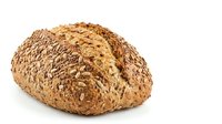 Freshly baked multigrain bread loaf with sunflower and flax seeds, isolated on white background, perfect for food and bakery projects.