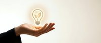 Business professional hand presenting glowing lightbulb with plant sprout inside symbolizing green innovation, sustainable ideas and eco-friendly solutions.