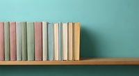 Row of colorful books arranged on wooden shelf against turquoise wall creating minimalist home library display for interior design and education concepts.