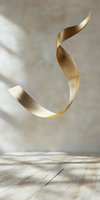 Elegant golden spiral ribbon floating in air against light gray background and wooden surface, with soft natural shadows creating depth and movement.