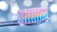 Colorful toothbrush with rainbow bristles and water droplets against soft bokeh background for dental hygiene and oral care concepts.