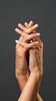 Two hands intertwined in an expressive gesture against a neutral gray background, conveying connection, unity, support, and emotional bonding for relationship and wellness concepts.