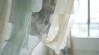 Soft flowing curtains in pastel green and cream tones creating elegant window treatment with natural light filtering through delicate translucent fabric layers.
