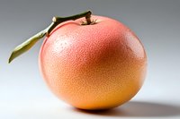 Fresh ripe grapefruit with green leaf and textured peel on light background, macro shot showing detailed citrus skin surface and natural gradient color.
