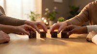 Business teamwork concept with hands building wooden blocks together on office desk representing collaboration and partnership strategy.
