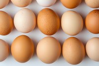 Fresh brown and white chicken eggs arranged in neat rows on light background, viewed from above. Natural organic food concept for healthy eating.