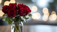 Deep red roses in clear glass vase against soft bokeh background, romantic mood with blurred lights creating dreamy atmosphere for valentines, weddings, and celebrations.