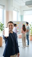 Smiling Caucasian businessman showing blank smartphone screen in modern office with team brainstorming on whiteboard in background for app presentation.