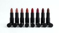 Collection of eight matte lipsticks in nude to deep berry shades arranged in row on white background for beauty and cosmetics branding.