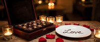 Romantic candlelit table with luxury chocolates in wooden box, Love plate, and red rose petals for Valentine's Day celebration.