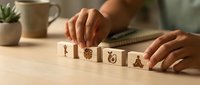 Woman arranging wooden blocks with love symbols on desk creating romantic message for Valentine's Day celebration and relationship concepts.