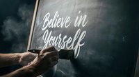 Hand writing motivational quote Believe in Yourself on a chalkboard with a brush, inspiring self-confidence and personal growth concept.