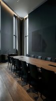 Modern conference room with wooden table and black chairs, featuring floor-to-ceiling windows with gray curtains and minimalist dark walls, suitable for corporate meetings and business presentations.