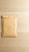 Brown kraft paper envelope on wooden desk surface for business correspondence and mailing needs.