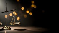 Golden scales of justice on dark background with warm bokeh lights creating elegant legal concept for law firm branding and attorney services.