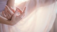 Delicate hands in soft pink light creating a gentle, open gesture suggesting peace, spirituality, or mindfulness for wellness and meditation content.