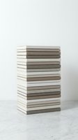 Stack of neutral colored books with blank covers arranged in neat pile on marble surface against white background for minimalist design projects.