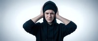 Young Asian man in black hoodie holding head in hands expressing stress, headache, mental health struggles, depression, anxiety, overwhelm, burnout concept.