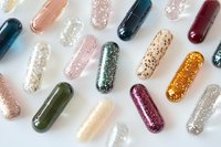 Colorful glitter-filled capsule pills scattered on white background, sparkling supplement concept for health, beauty, and wellness design projects.