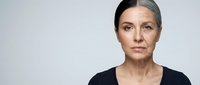 Middle-aged Caucasian woman with half gray hair showing natural aging process against neutral background for beauty and skincare concepts.