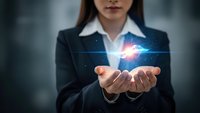 Professional businesswoman in dark suit holding glowing digital energy sphere with network connections in cupped hands representing innovation and technology.