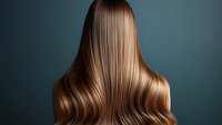 Long wavy brown hair from back view against teal background, showing smooth glossy texture and professional salon styling for beauty and haircare advertising.