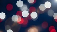 Festive bokeh lights background with red and white circular blur effects creating magical holiday atmosphere for celebrations and decorative designs.