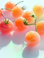 Fresh ripe cherry tomatoes with water droplets on glossy surface creating colorful reflections for culinary and healthy eating concepts.