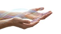 Cupped hands with glowing energy waves and light rays creating magical healing aura for wellness and spiritual concepts.