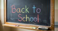 Back to school message written in colorful chalk on classroom blackboard with wooden frame and chalk pieces on ledge for education concepts.